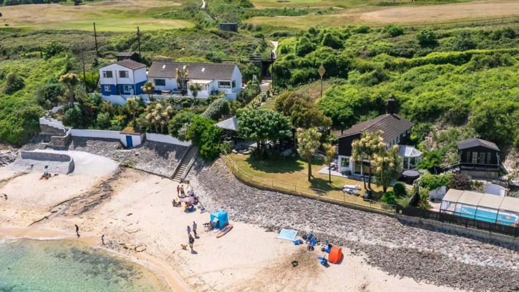 Three Beach Houses with pool, hot tubs and lawned garden above a sandy beach with people sunbathing and paddling with a Links Golf Course directly behind and everyone enjoying a summer sunny day